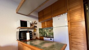 A compact kitchen with wooden cabinets, a microwave, a toaster, and a refrigerator. - 28m² Studio at the slopes base, 4 pax, Les Cimes residence (Enchastrayes)