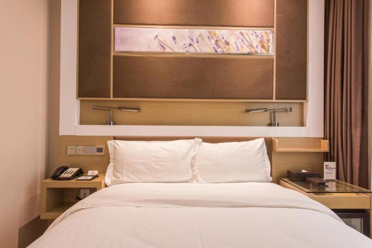 Une chambre d’hôtel comprenant un lit, des tables de chevet, un téléphone et une œuvre d’art accrochée au mur.