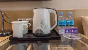 Una zona de cocina con un hervidor eléctrico blanco, dos tazas blancas y dos botellas de agua sobre una bandeja.