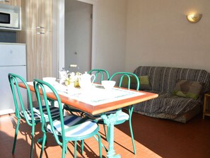 Uma sala de jantar com uma mesa de madeira, cadeiras verde-água e um sofá estampado.