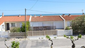 A row of houses with red-tiled roofs, a white fence, and a view of the sea.