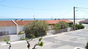A residential street with houses, a clear sky, and a view of the sea.