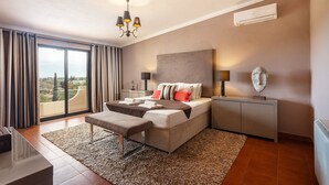 A modern hotel room with a large bed, a bench, a desk, and a view of the city. - Luxury 3-Bedroom Countryside Villa with Pool, Quelfes (Quelfes)