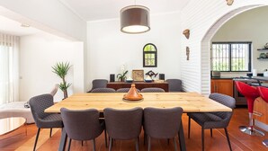 A modern dining area with a wooden table, grey upholstered chairs, and a pendant light. - Luxury 3-Bedroom Countryside Villa with Pool, Quelfes (Quelfes)