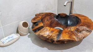 A unique, circular wooden sink with a modern faucet, placed on a tiled floor next to a stone container and a small white sign. - Luxury 3-Bedroom Countryside Villa with Pool, Quelfes (Quelfes)