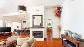A spacious living room with a fireplace, a dining area, and a kitchen visible through an archway. - Luxury 3-Bedroom Countryside Villa with Pool, Quelfes (Quelfes)
