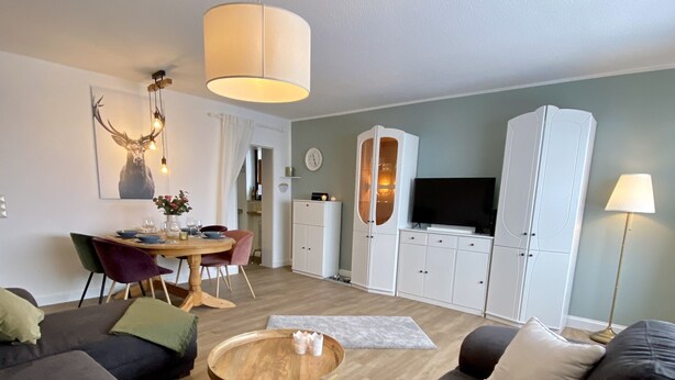 Una sala de estar moderna con un sofá grande, una mesa de comedor con sillas, un televisor y un mueble.