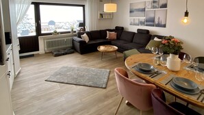 Una sala de estar moderna con un sofá oscuro, una mesa de centro redonda y un comedor con platos y vasos.