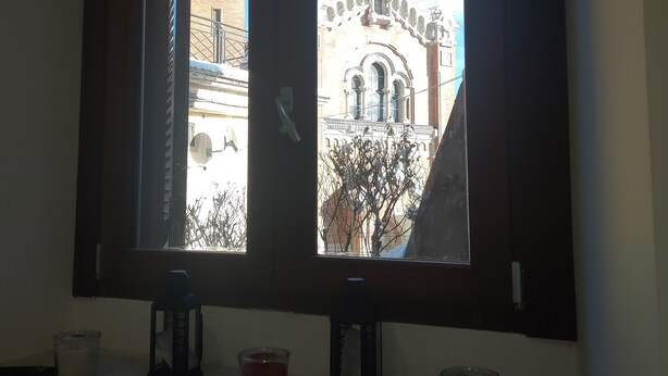 A room with a window overlooking a building with a distinctive architectural style. - Little Paradise in the center of Rivisondoli (Rivisondoli)