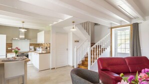 A modern living room with a red sofa, a grey armchair, and a dining area with a kitchen in the background. - Family house with secure garden and terrace (Bricquebec-en-Cotentin)