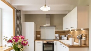 A modern kitchen with white cabinets, a wooden countertop, a built-in oven, and a hanging light fixture. - Family house with secure garden and terrace (Bricquebec-en-Cotentin)