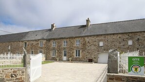 A stone building with a gravel driveway and a white gate. - Family house with secure garden and terrace (Bricquebec-en-Cotentin)