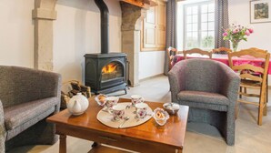 A cozy room with a fireplace, a dining table with chairs, and a sofa. - Family house with secure garden and terrace (Bricquebec-en-Cotentin)