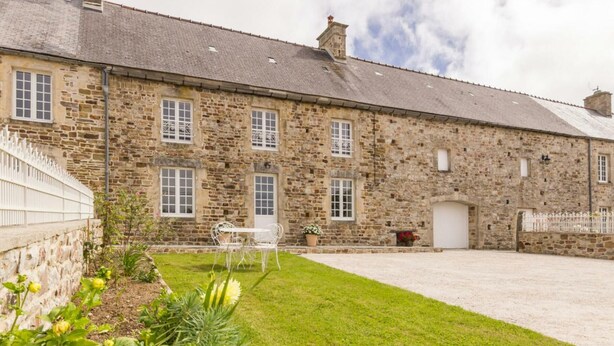 A stone building with multiple windows and a covered driveway. - Family house with secure garden and terrace (Bricquebec-en-Cotentin)