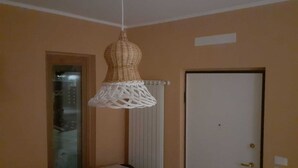 Une pièce avec un luminaire suspendu en fibres tressées, une porte et un radiateur.
