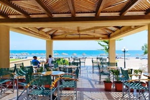 Un espace extérieur aménagé avec des tables et des chaises, offrant une vue sur la plage.