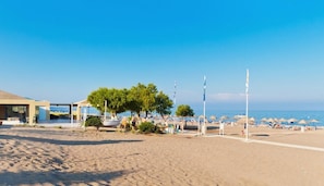 Une plage avec des parasols, un bâtiment et un ciel dégagé.