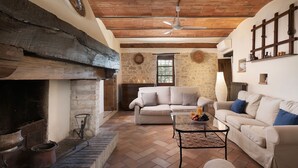 A cozy living room with a fireplace, stone walls, and a wooden ceiling. - Villa Di Morice 14, Emma Villas (Castel Ritaldi)
