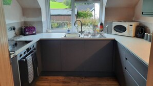 Una cocina moderna con una isla central, horno integrado, microondas y una ventana con vistas a zonas verdes.
