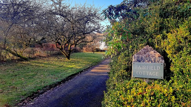 Un sendero lleva a un cartel que dice 'FAIRFIELD COTTAGE'.
