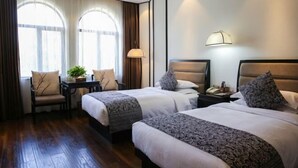 A hotel room with two beds, a desk, a chair, and a lamp. - Yuetu International Hotel (Shangrao)