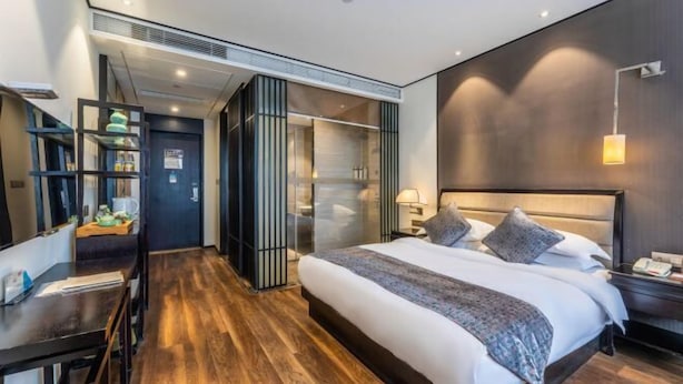 A modern hotel room with a large bed, a desk, and a walk-in closet. - Yuetu International Hotel (Shangrao)
