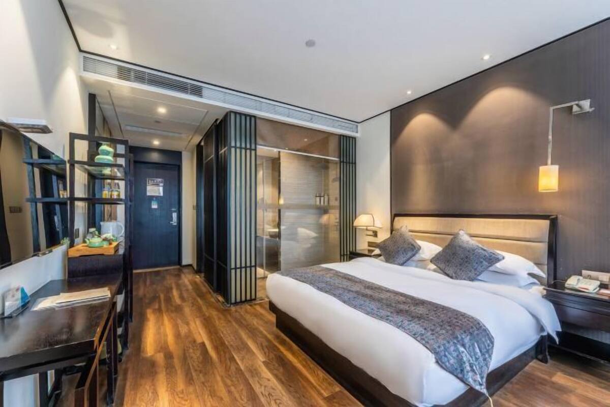 Moderni hotellihuone, jossa on suuri sänky, työpöytä ja erillinen vaatehuone.