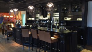 A bar area with a long counter, multiple stools, and hanging pendant lights. - Comfortable Chalet With Dishwasher, Near Maastricht (Susteren)