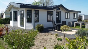 A modern two-story house with a patio area, large windows, and a well-maintained garden. - Well-kept Chalet not far From the Biesbosch (Dordrecht)