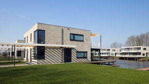 A modern building with a flat roof, large windows, and a brick facade. - Luxury Villa With Jetty, at the Veerse Meer (Arnemuiden)
