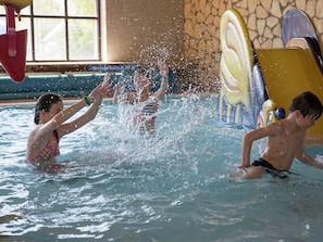 A swimming pool with children playing and splashing water.