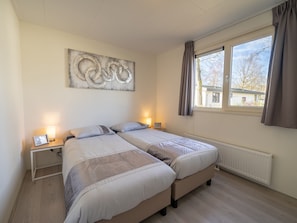 A bedroom with two beds, a large abstract painting on the wall, and a window with curtains.