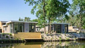 A modern house with a wooden deck and a pond in front. - Modern Chalet With Garden, in Green Kempen (Mol)