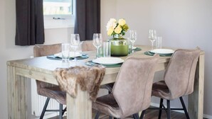 A dining table set with plates, glasses, and a vase of flowers.
