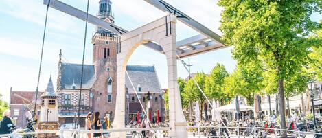 Un pont doté d’une passerelle pour piétons, un canal et un bâtiment historique avec une tour en arrière-plan.
