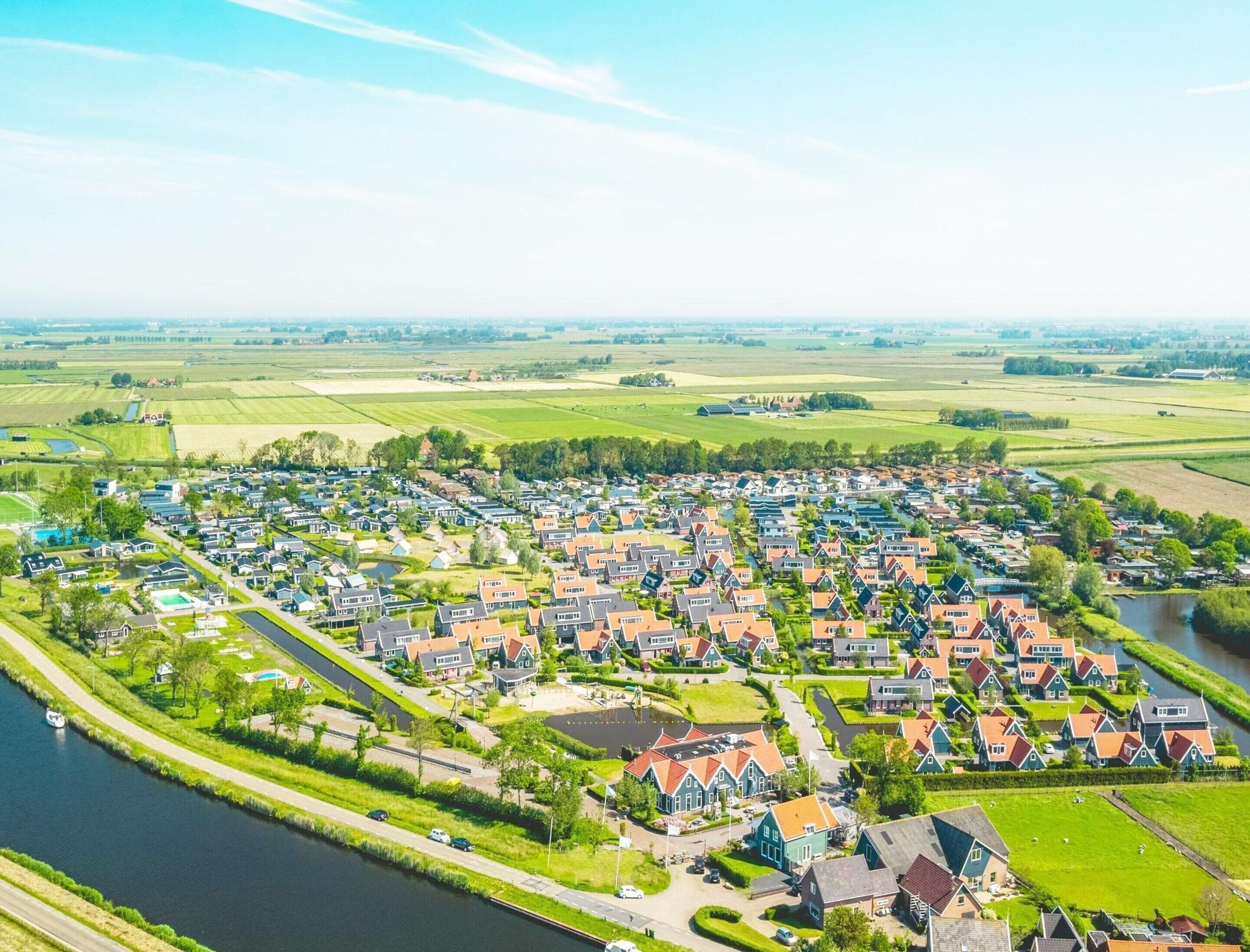 Ett bostadsområde med hus, en kanal och öppna fält.