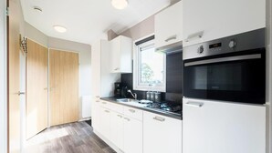 A modern kitchen with white cabinets, a black stove, and a window above the sink.