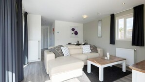 A modern living room with a sofa, a coffee table, and a view of the outside.