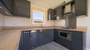 Una cocina moderna con armarios oscuros, una isla central y un horno empotrado.