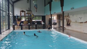 Una piscina con una estructura de juegos con temática de barco y un mural de un barco velero.