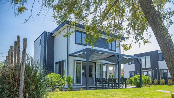 A modern two-story house with a covered patio, a grassy yard, and a wooden fence. - Modern, Spacious, Detached Holiday Home, Near Alkmaar (West-Graftdijk)
