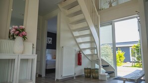 A spacious interior with a white staircase, a wooden bench, and a view of the outside. - Modern, Spacious, Detached Holiday Home, Near Alkmaar (West-Graftdijk)