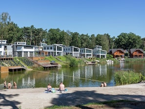 A lakeside resort with modern cabins, a sandy beach, and a calm lake. - Modern Chalet With Combi-microwave (Brunssum)