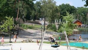 A park with a swing set, picnic tables, and a lake. - Modern Chalet With Combi-microwave (Brunssum)