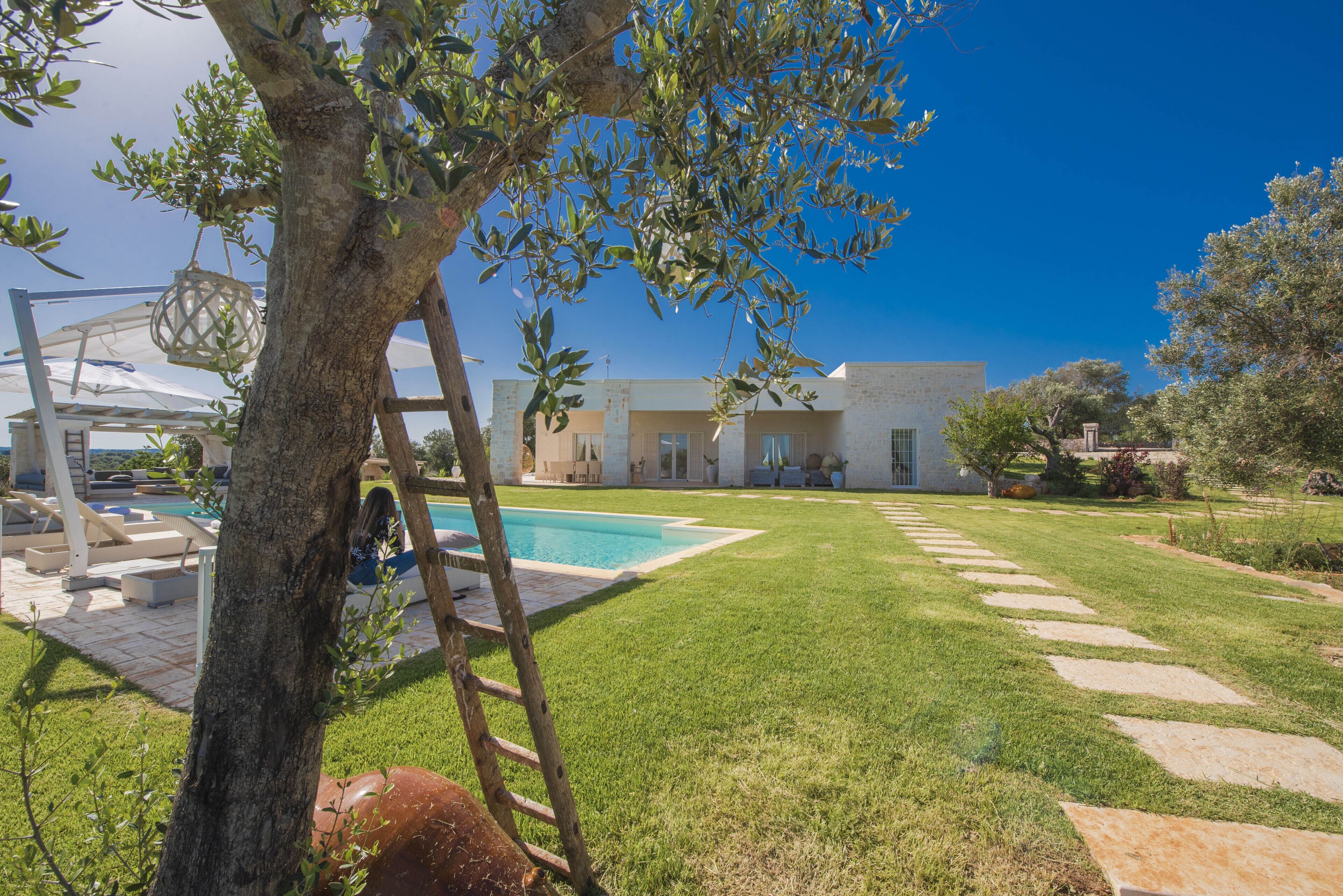 A modern house with a swimming pool, a well-maintained lawn, and a stone pathway.