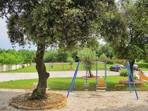 Un parque infantil con columpios y un árbol en el centro.