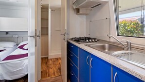 A compact kitchenette with a gas stove, sink, and a window with a view of greenery. - Mobile Home in Banjole Near Centinera Beach (Medulin)