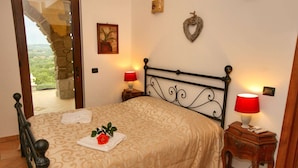Une chambre à coucher comprenant un lit, deux tables de chevet avec des lampes, un élément décoratif fixé au mur et une porte donnant sur un balcon.