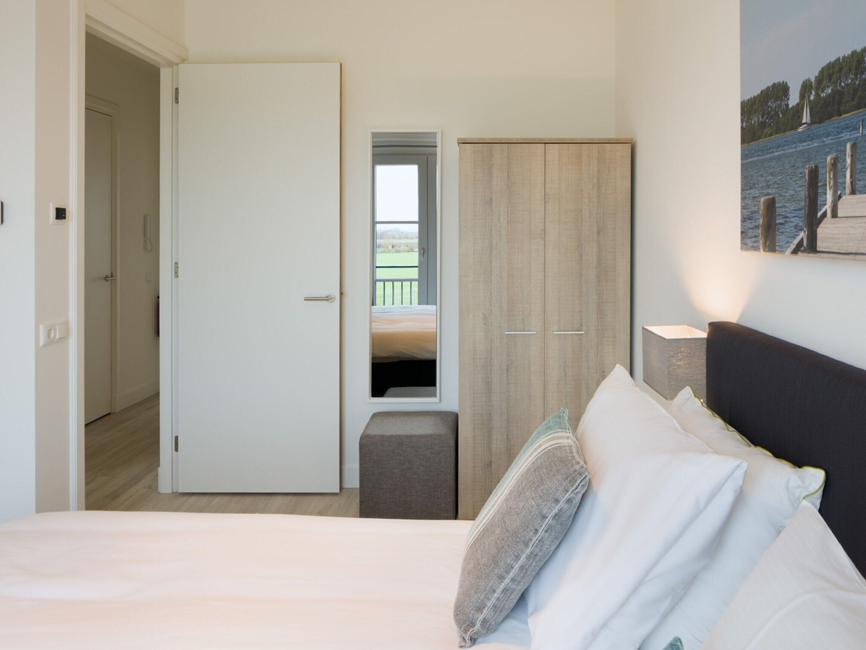 A bedroom with a bed, a wardrobe, and a view of a balcony.