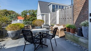 A patio with a table and chairs, potted plants, and a brick wall. - Beautiful Well Equipped Apartment Near the Beach (Domburg)